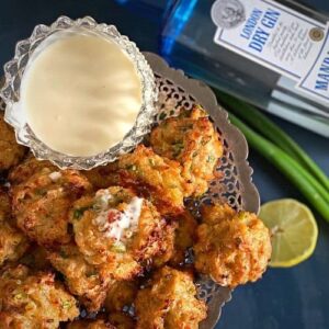 Simple chicken balls with homemade gin mayonnaise on a silver tray with half a lime, spring onion and a bottle of gin; recipe image