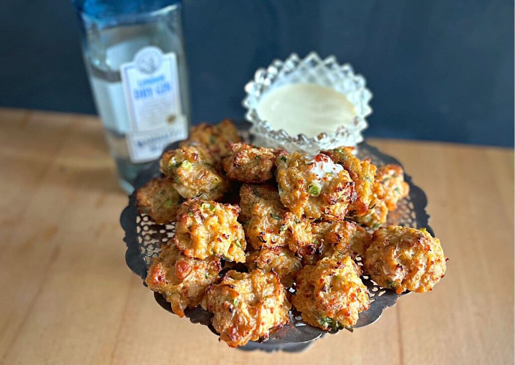 Simple chicken balls with homemade gin mayonnaise on a silver tray, with a bottle of gin in the background.